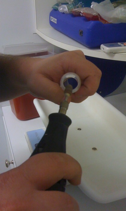 the closed plastic end of the syringe case was dremeled away, now the technician smooths the edges